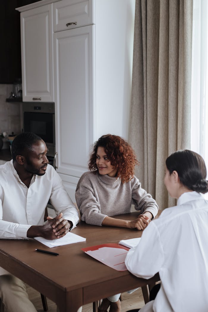 A diverse couple discusses with a consultant at home, capturing a casual business meeting.